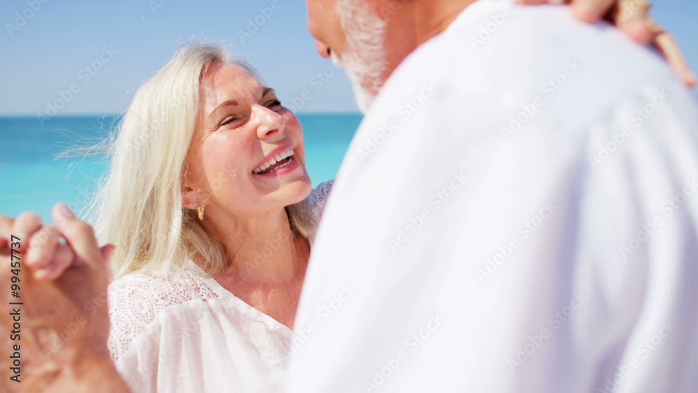 Loving retired Caucasian couple dancing together on a beach Loving retired Caucasian couple dancing together on a beach