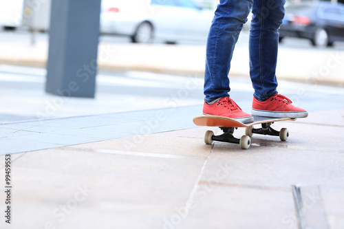 young skateboarder legs riding on skateboard on city