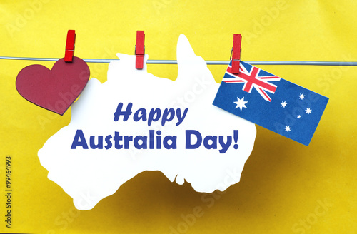 Celebrate Australia Day holiday on January 26 with a Happy Australia Day message greeting written across white Australian maps (red heart) and flag hanging pegs on red background. Toned collage
