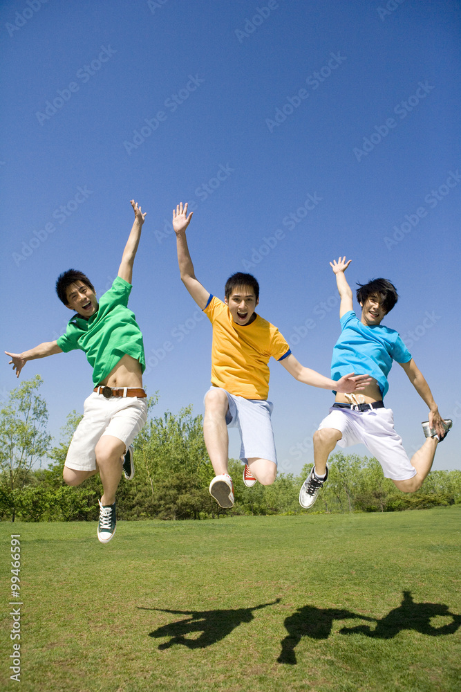 Fototapeta premium Three young men jumping in the air at the park