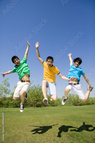 фотографія Three young men jumping in the air at the park