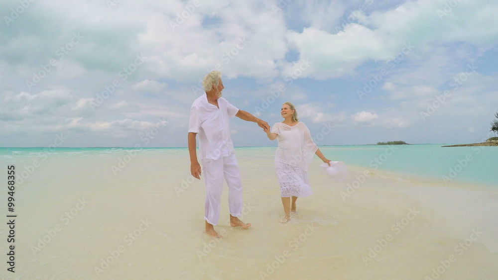 Male female senior Caucasian couple wearing casual white clothes on beach Male female senior Caucasian couple wearing casual white clothes on beach