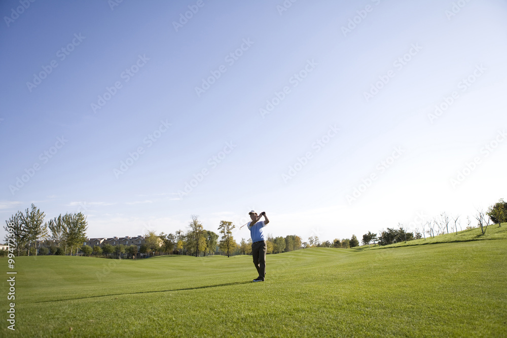 Man swinging golf club on golf course Man swinging golf club on golf course