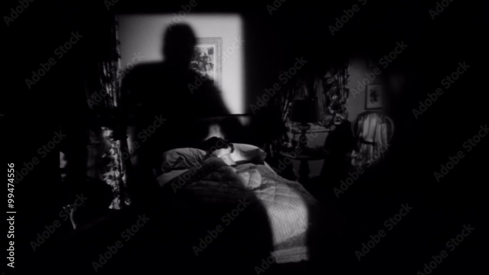 Shadow of man moving towards woman sleeping in bed