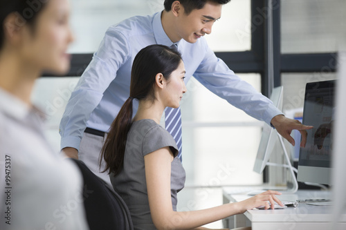 Young businesswoman and businessman talking in office