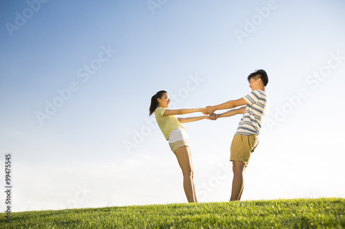 Cheerful young couple holding hands on grass