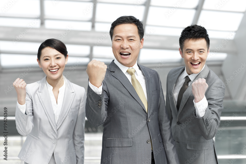Cheerful business team punching the air at the airport Cheerful business team punching the air at the airport