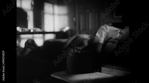 Sleepy man turning over alarm clock at 7am, 1940s photo
