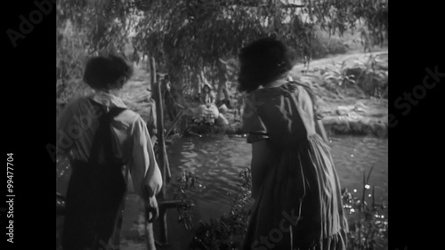 Young boy and girl walking next to river, 1940s photo