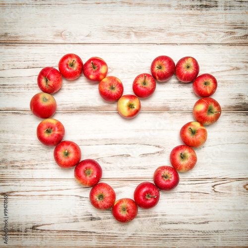 Red apples heart wooden background. Love concept vintage