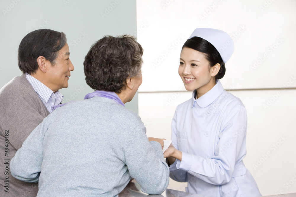 Young Nurse Helping Senior Couple at Nurses' Station Young Nurse Helping Senior Couple at Nurses' Station