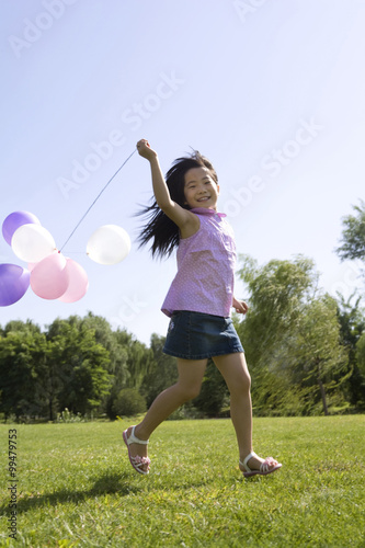 Young girl running with balloon outdoors © Blue Jean Images