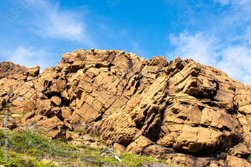 Large irregular cracked rock outcrop against sky