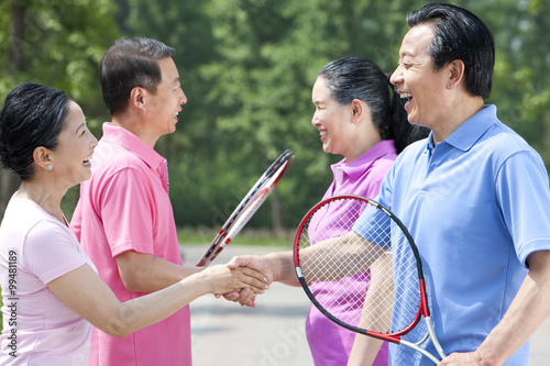 Senior couples playing tennis in park © Blue Jean Images