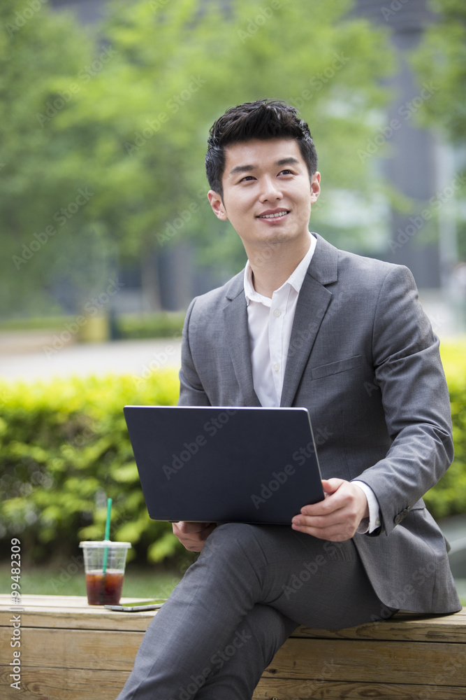 Young businessman working with laptop outdoors Young businessman working with laptop outdoors