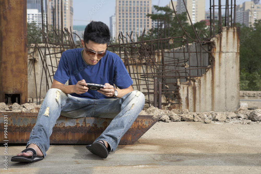 Man Playing Portable Video Game In Construction Site