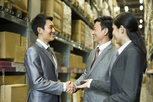 Business people shaking hands in warehouse