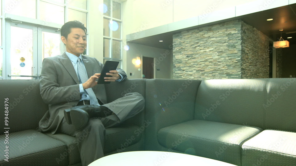 Asian American city business male on office atrium with wireless tablet Asian American city business male on office atrium with wireless tablet
