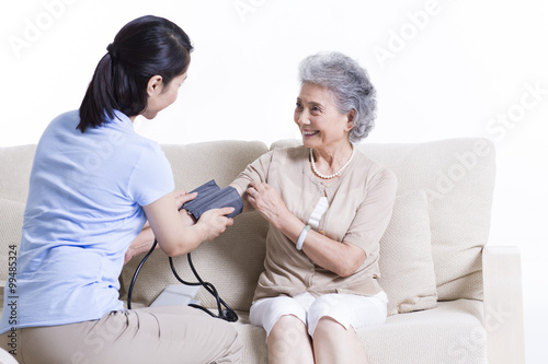 Nursing assistant taking senior woman s blood pressure