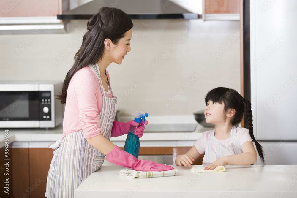 Fototapeta premium Mother and daughter cleaning kitchen counter