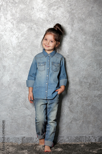 Portrait of little fashion kid girl on gray wall background © Africa Studio