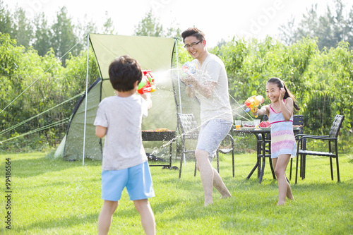 Happy father and children playing squirt guns