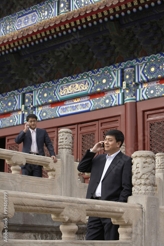 Two Businessmen Talking On Cellphones In The Forbidden City In Beijing photo