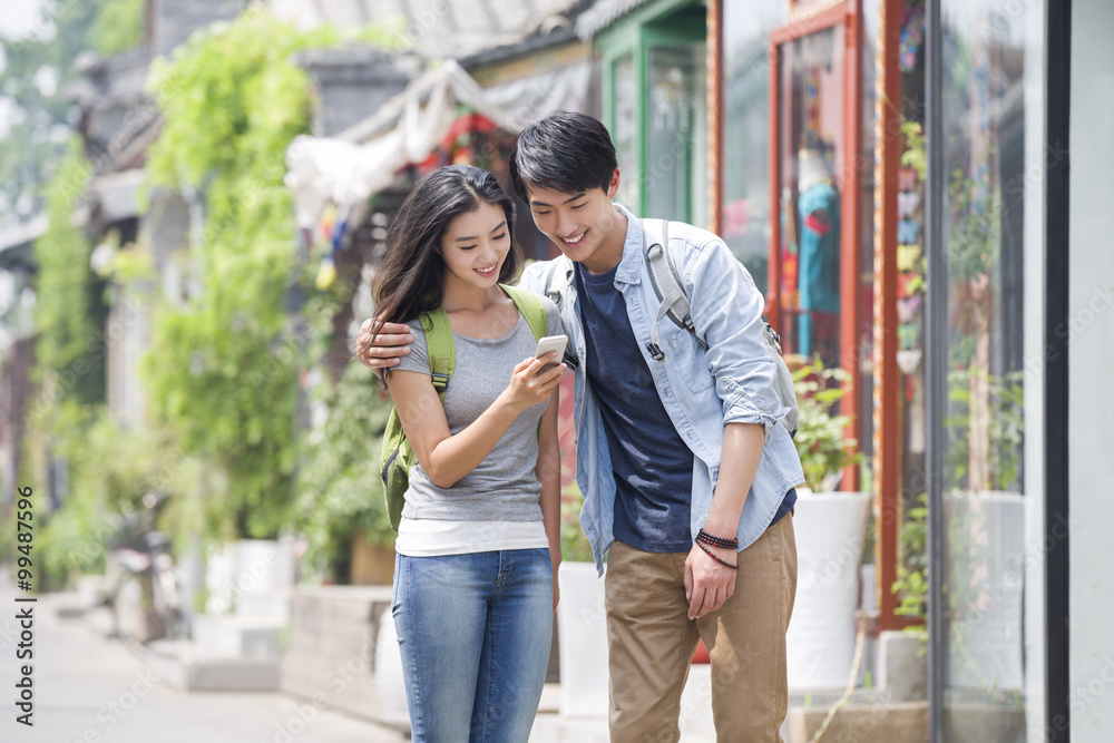 Young couple travelling in Beijing Hutong with smart phone
