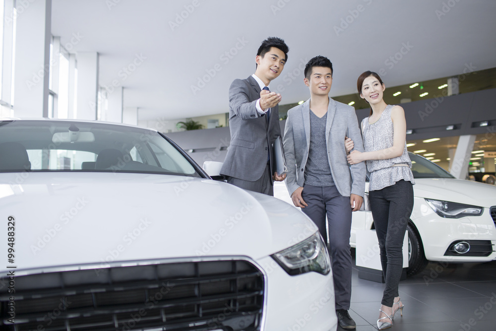 Young couple choosing car in showroom Young couple choosing car in showroom