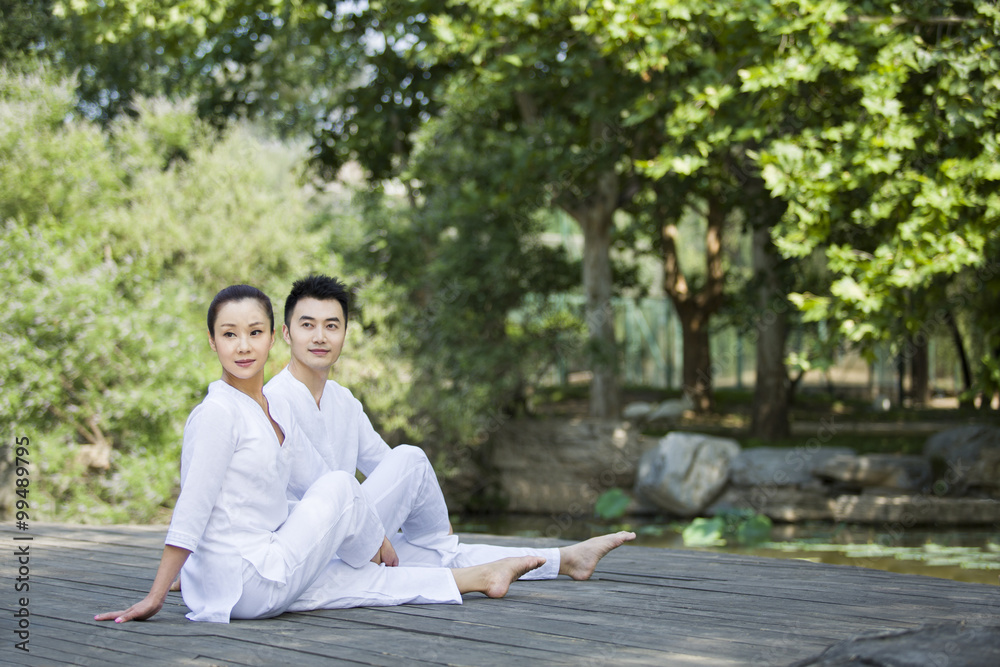 Man and woman practicing yoga on a wooden dock Man and woman practicing yoga on a wooden dock