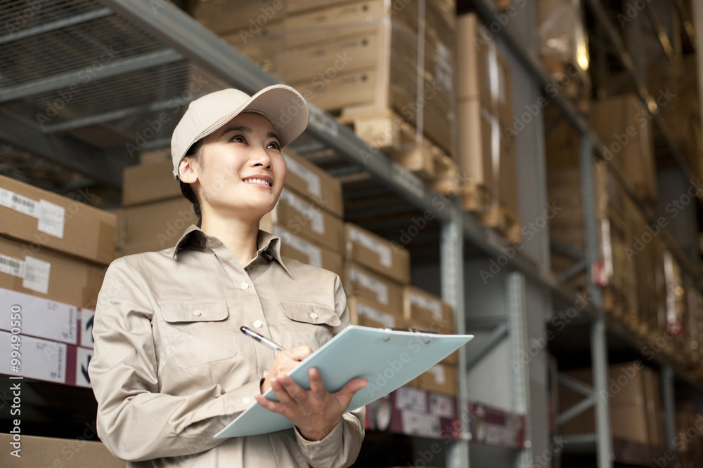 Female Chinese warehouse worker with clipboard Female Chinese warehouse worker with clipboard