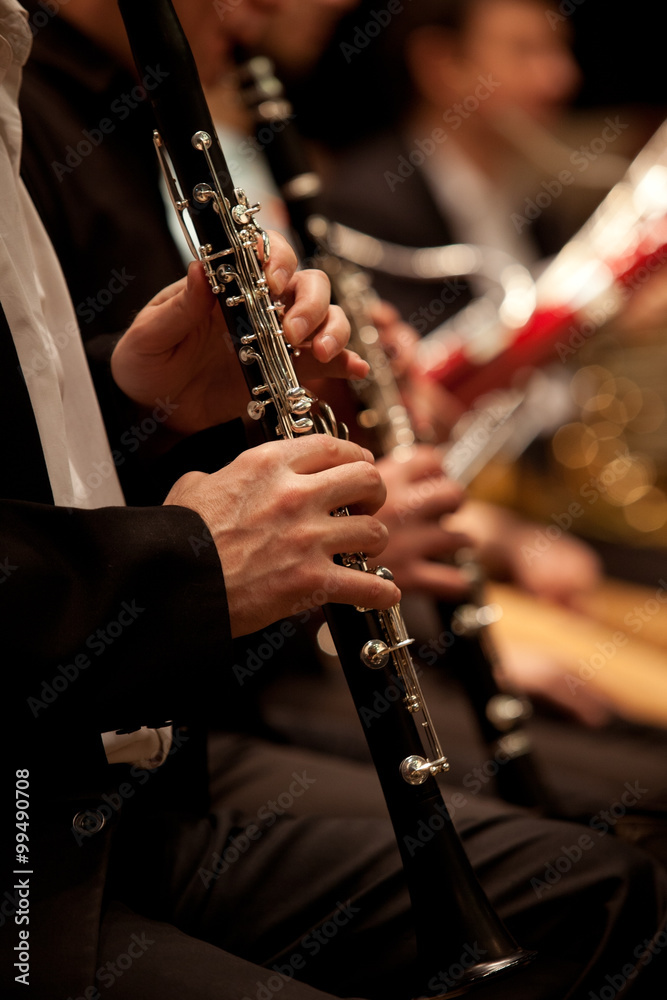Fototapeta premium Hands of man playing the clarinet in the orchestra in dark colors