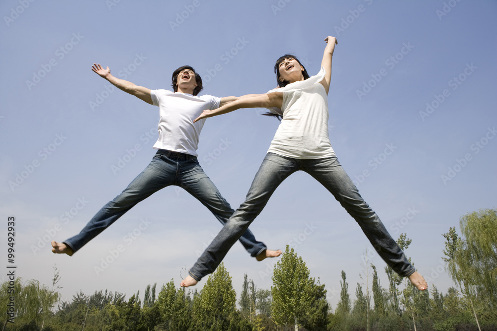 Young couple jumping in mid-air Young couple jumping in mid-air