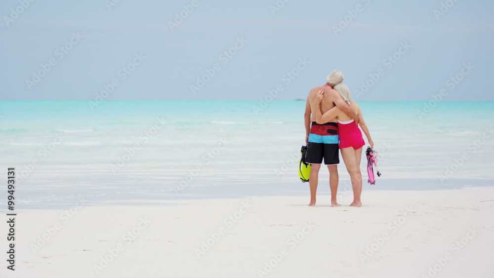Caucasian senior travellers in swimwear on a beach with snorkels Caucasian senior travellers in swimwear on a beach with snorkels