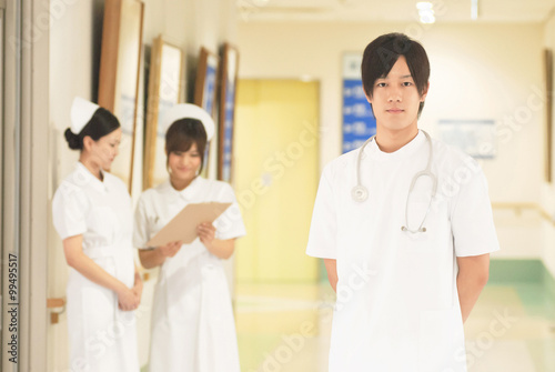 病院内に立つ若い男性看護師と医療スタッフ