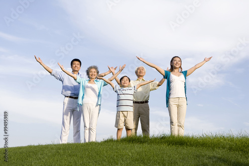 Family standing on the grass, arms outstretched