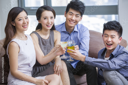 Wall Mural Happy young friends drinking cocktail in living room