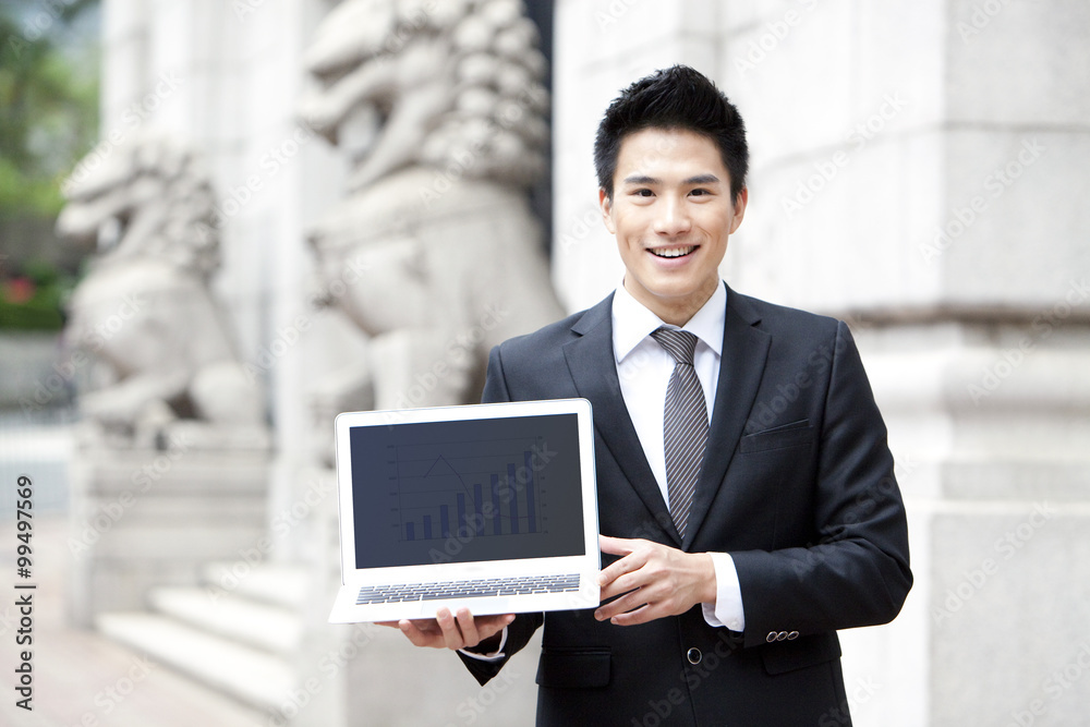 Happy young businessman with a laptop outdoors, Hong Kong Happy young businessman with a laptop outdoors, Hong Kong