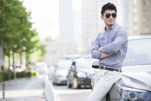 Young man leaning against his car © Blue Jean Images
