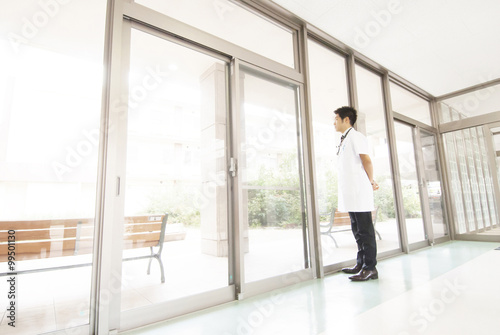 病院の廊下に立ち外を眺める男性医師