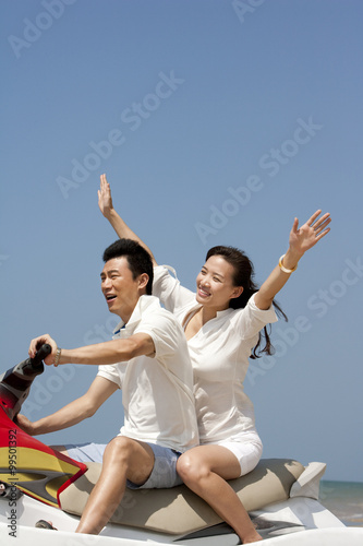 Happy couple riding on a jet ski