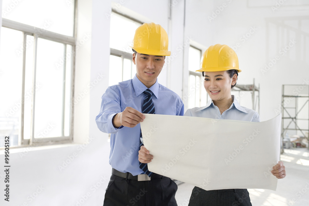 Two colleagues discussing a blueprint Two colleagues discussing a blueprint