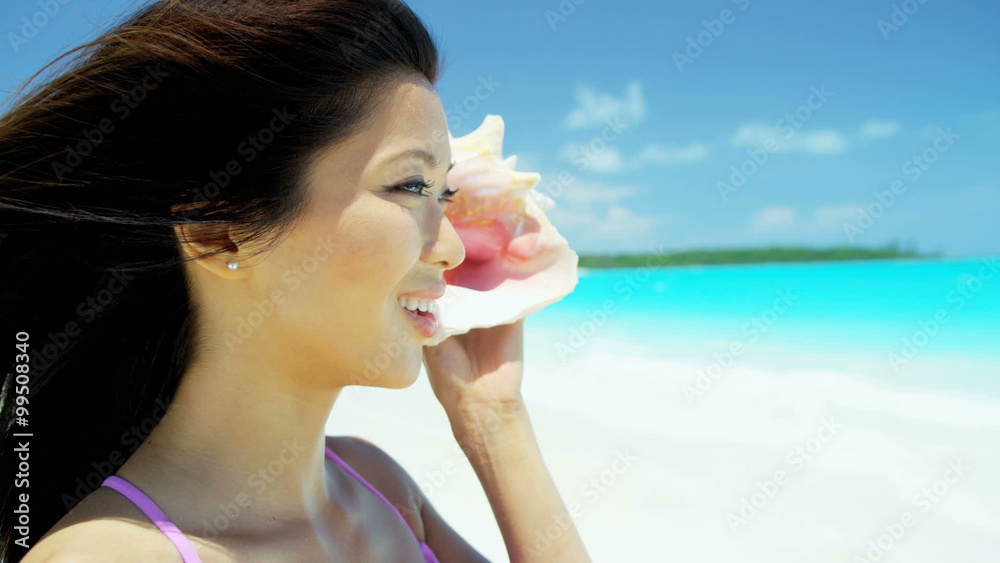 Beautiful Asian Chinese girl holding conch shell on tropical beach