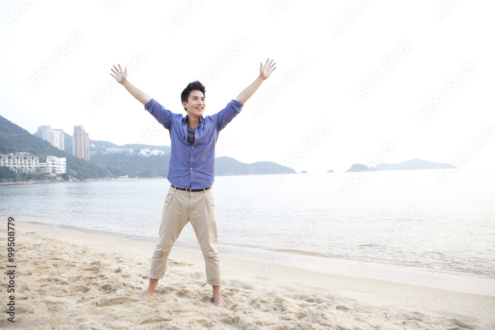 Cheerful young man arms outstretched on the beach of Repulse Bay, Hong Kong Cheerful young man arms outstretched on the beach of Repulse Bay, Hong Kong
