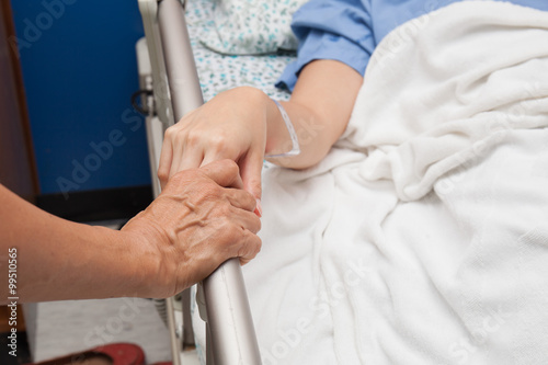 A old wrinkled hand touches and holds young hand