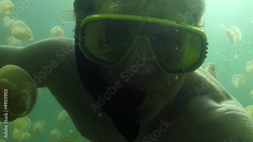 Jellyfish Lake, Palau Island, Micronesia, Pacific Ocean. Summer fun, recreation, holidays, vacation, water sport. Man swimming underwater, apnea free diving, snorkeling, holding GoPro video camera