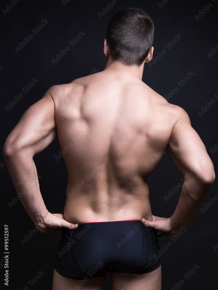 handsome young bodybuilder with toned body posing shirtless