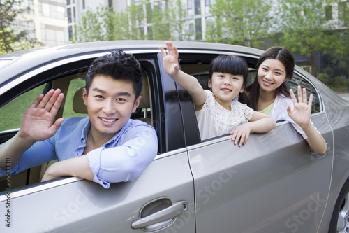 Happy young family waving out of car window © Blue Jean Images