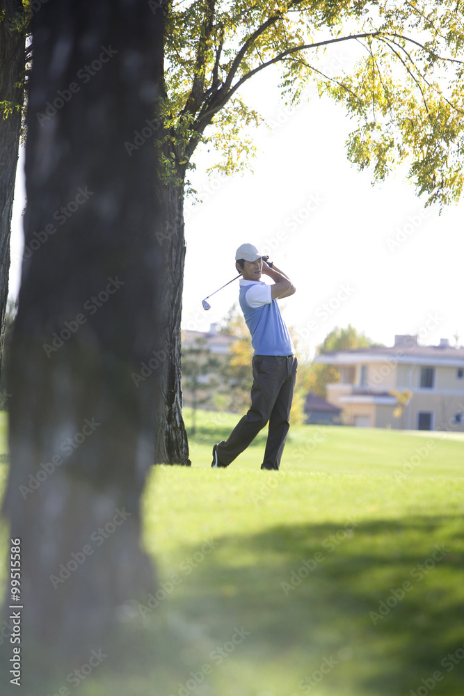 Man swinging golf club on golf course Man swinging golf club on golf course