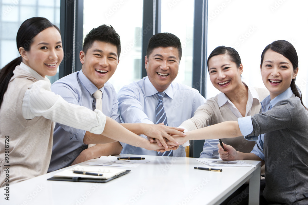 Businesspeople putting their hands in the middle Businesspeople putting their hands in the middle